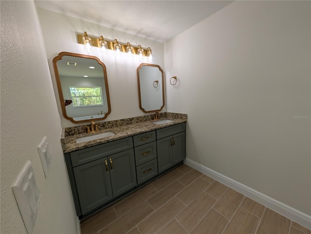full bathroom featuring a sink, baseboards, and double vanity