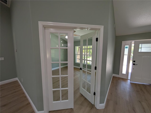 foyer entrance featuring visible vents, a ceiling fan, baseboards, wood finished floors, and vaulted ceiling