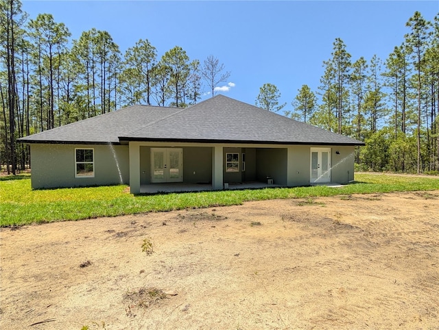 back of house with french doors, stucco siding, and roof with shingles