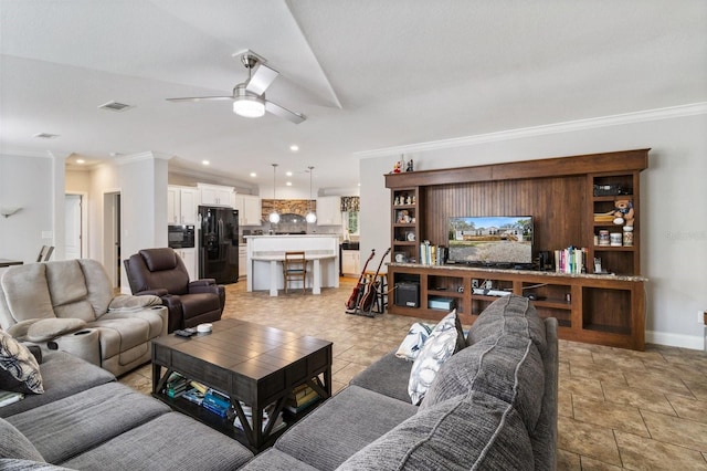 living room featuring crown molding, a ceiling fan, baseboards, visible vents, and ornate columns