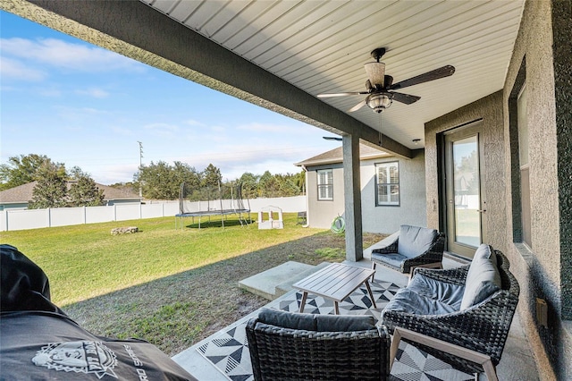 view of patio featuring ceiling fan, a trampoline, and a fenced backyard