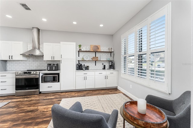 kitchen featuring stainless steel appliances, wall chimney range hood, light countertops, and white cabinets