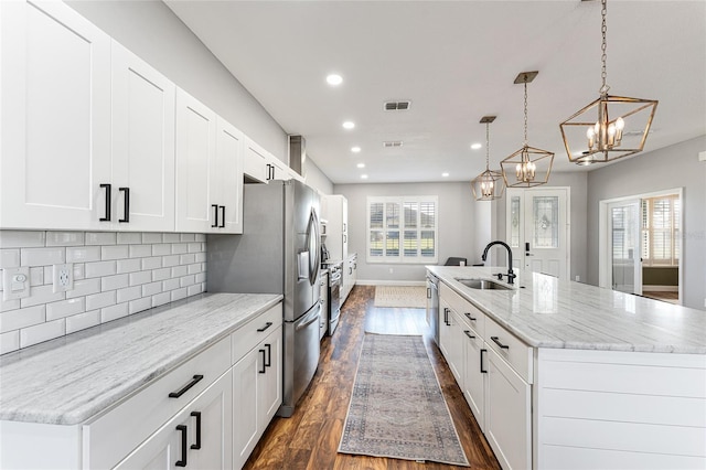 kitchen with a spacious island, a sink, white cabinetry, visible vents, and pendant lighting