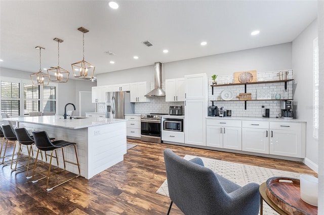 kitchen with a kitchen island with sink, appliances with stainless steel finishes, a sink, and white cabinetry