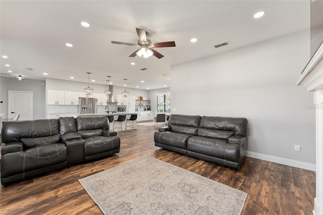 living room featuring visible vents, baseboards, a ceiling fan, dark wood-type flooring, and recessed lighting