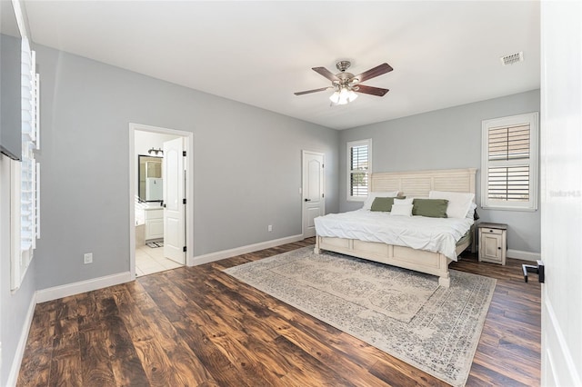 bedroom with baseboards, visible vents, a ceiling fan, ensuite bath, and wood finished floors