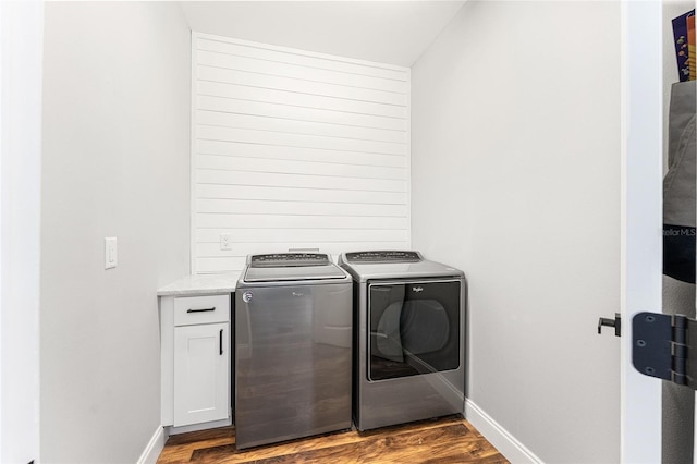 washroom featuring baseboards, cabinet space, washing machine and clothes dryer, and wood finished floors