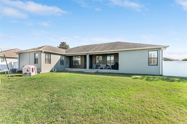 back of property featuring a lawn, central AC unit, and stucco siding