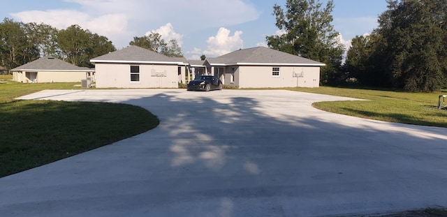 ranch-style home with curved driveway, a front lawn, and stucco siding