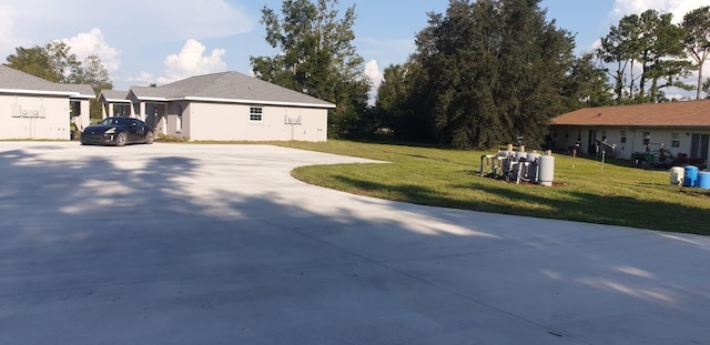 view of side of property featuring concrete driveway and a lawn