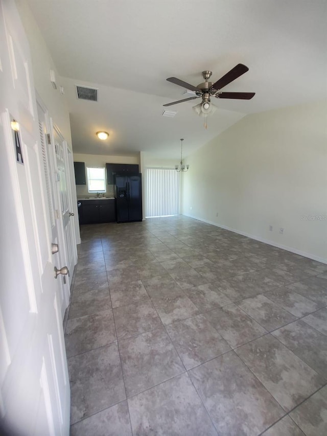 unfurnished living room with visible vents, vaulted ceiling, baseboards, and ceiling fan with notable chandelier