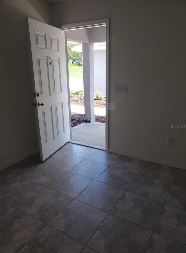 entryway featuring dark tile patterned floors and baseboards