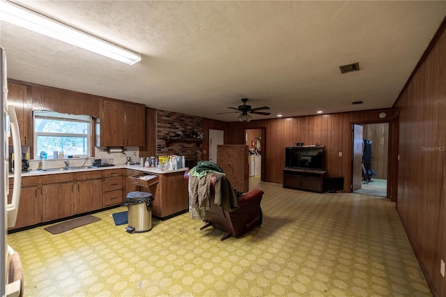 kitchen featuring wood walls, a sink, visible vents, open floor plan, and light countertops