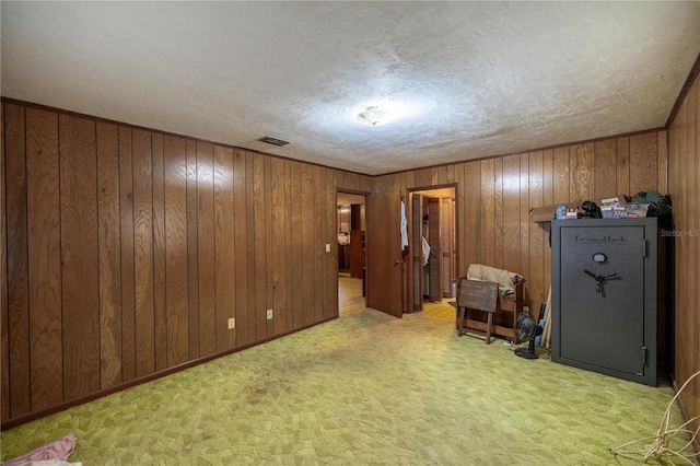 interior space with light carpet, wood walls, and visible vents