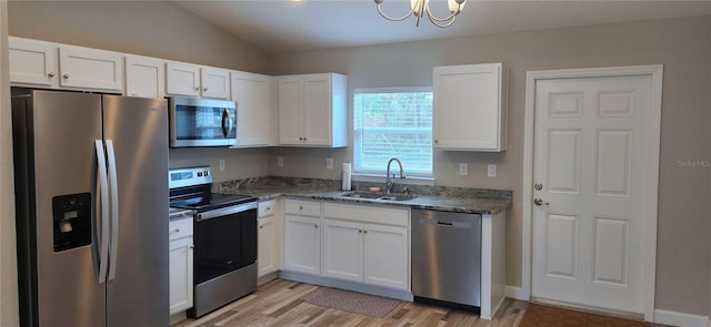 kitchen featuring stainless steel appliances, dark stone countertops, a sink, and white cabinetry