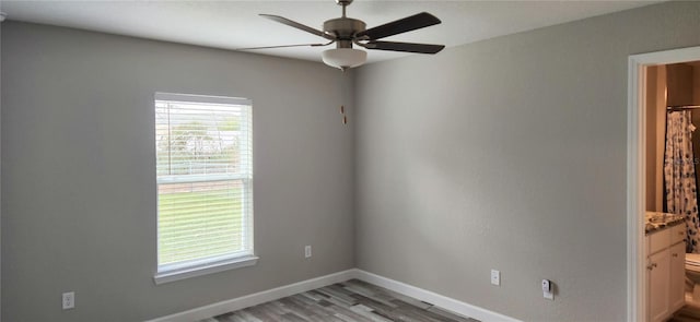 spare room with light wood-style flooring, a ceiling fan, and baseboards