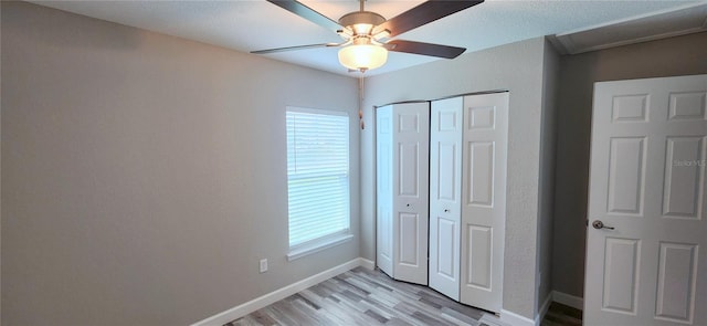 unfurnished bedroom featuring baseboards, multiple windows, a closet, and light wood-style floors