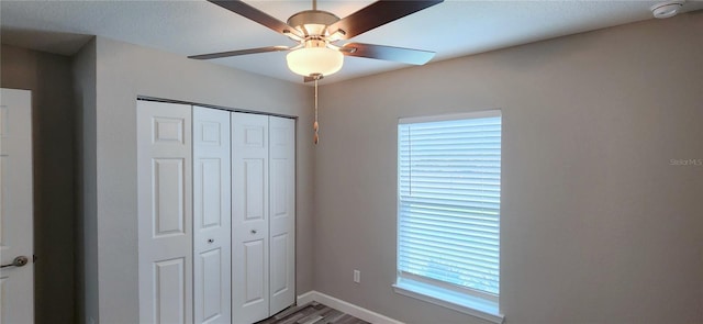 unfurnished bedroom with ceiling fan, baseboards, a closet, and wood finished floors