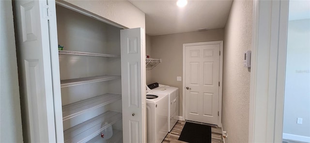 laundry area featuring laundry area, a textured wall, washing machine and clothes dryer, and wood finished floors