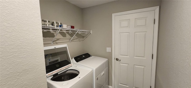 laundry room with a textured wall, laundry area, and separate washer and dryer