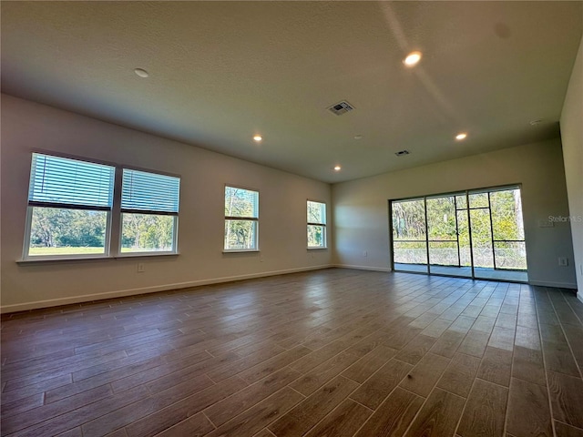 spare room with dark wood-type flooring, recessed lighting, visible vents, and baseboards