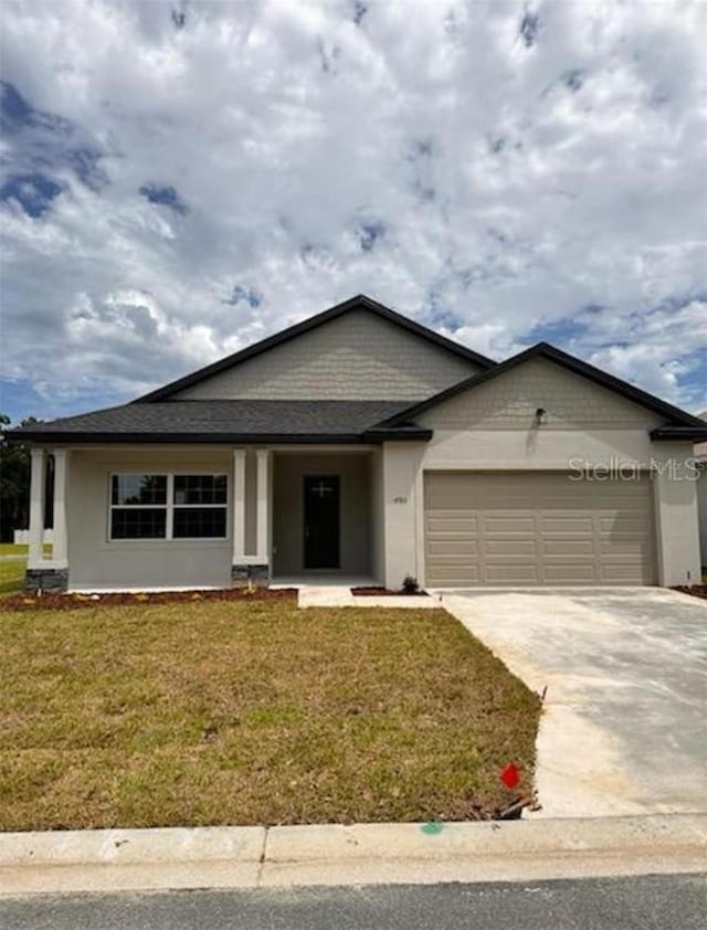 single story home with a garage, driveway, a front lawn, and stucco siding