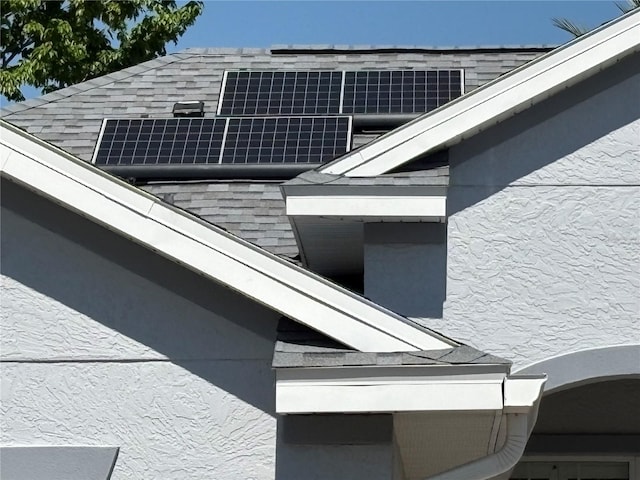 view of property exterior featuring a shingled roof and roof mounted solar panels