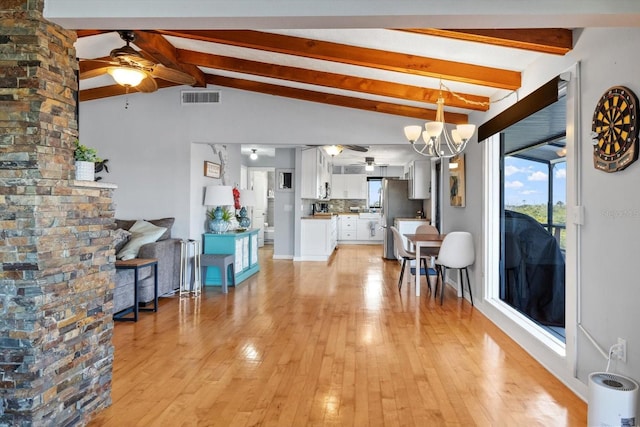 unfurnished living room with visible vents, light wood-style flooring, lofted ceiling with beams, and ceiling fan with notable chandelier