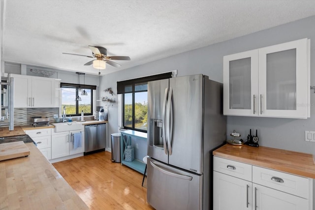 kitchen featuring white cabinets, light wood-style flooring, appliances with stainless steel finishes, wooden counters, and a sink