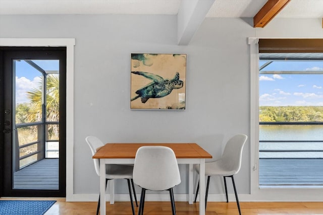 dining space featuring plenty of natural light, light wood-style flooring, and beamed ceiling