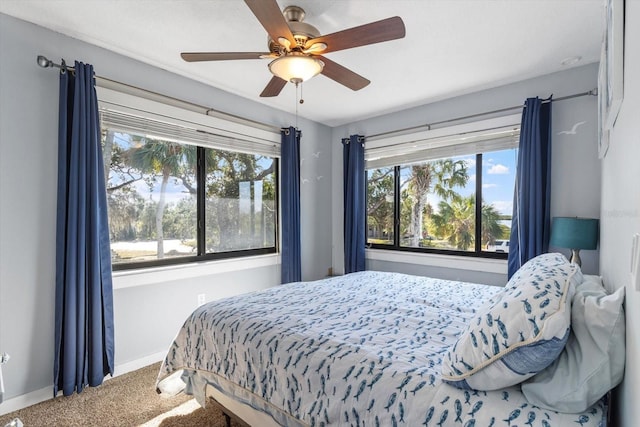 carpeted bedroom featuring ceiling fan, multiple windows, and baseboards