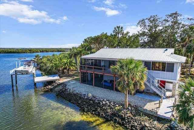 rear view of property featuring a sunroom, boat lift, metal roof, a water view, and stairs