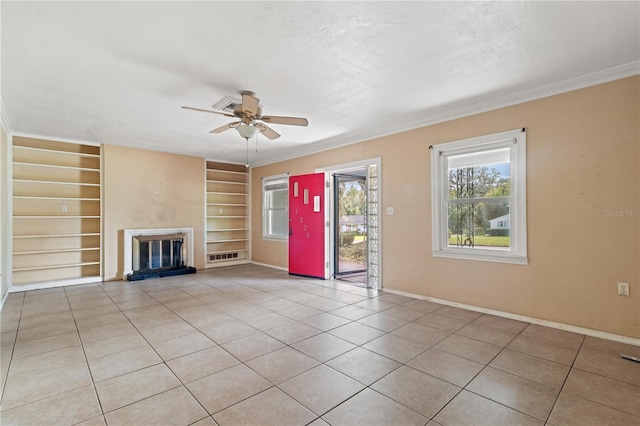 unfurnished living room with a textured ceiling, light tile patterned floors, a ceiling fan, built in features, and a glass covered fireplace