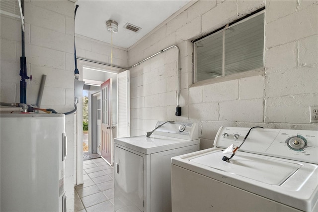 clothes washing area with concrete block wall, washing machine and clothes dryer, visible vents, electric water heater, and laundry area