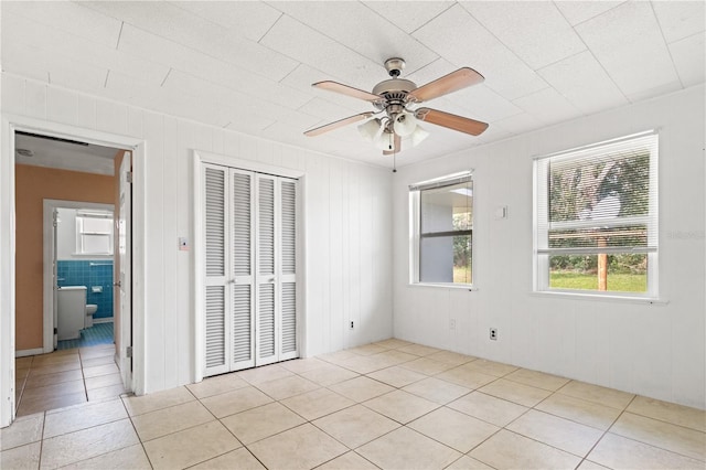 unfurnished bedroom with light tile patterned floors, ceiling fan, and a closet