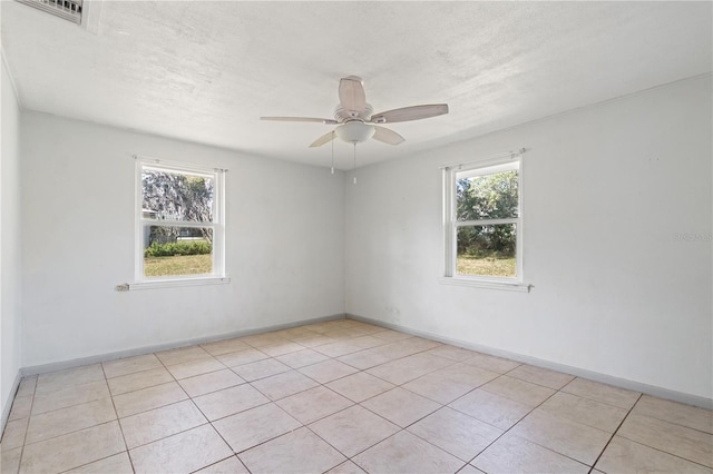 empty room with visible vents, ceiling fan, a textured ceiling, and baseboards