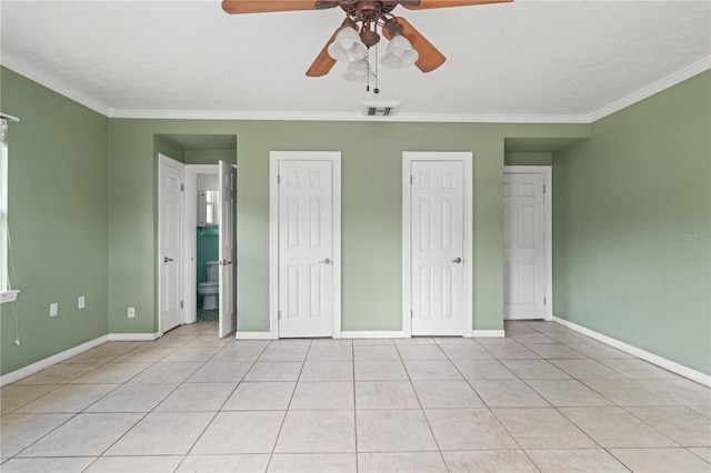 unfurnished bedroom featuring multiple closets, visible vents, crown molding, and light tile patterned floors