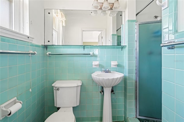 full bathroom with a stall shower, toilet, and tile walls