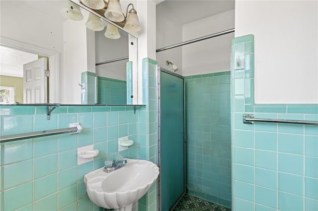 full bath with a sink, a wainscoted wall, a shower stall, and tile walls