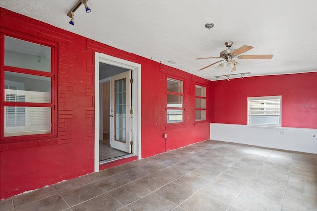 empty room featuring tile patterned flooring, ceiling fan, and track lighting