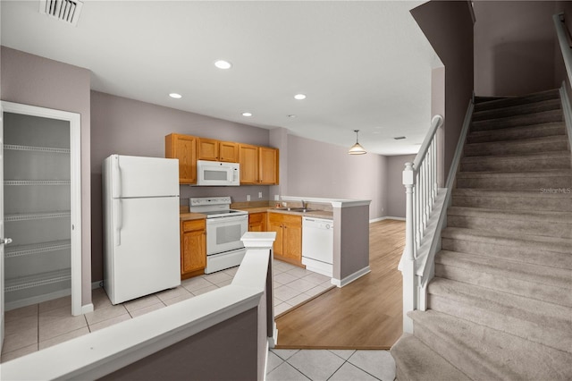 kitchen with white appliances, light tile patterned floors, a peninsula, a sink, and recessed lighting