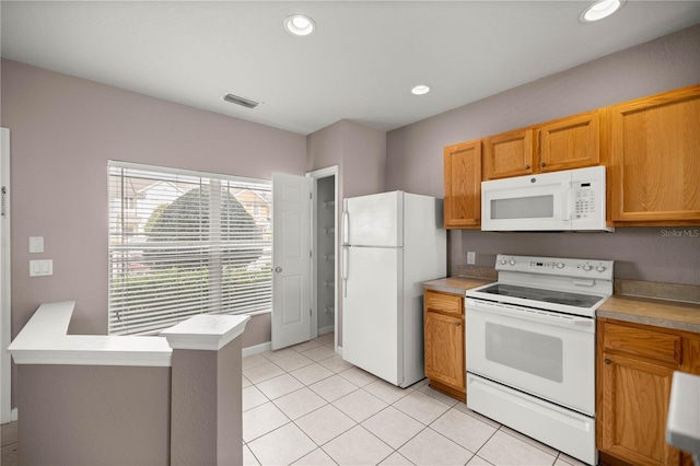 kitchen with brown cabinetry, recessed lighting, white appliances, and light tile patterned floors