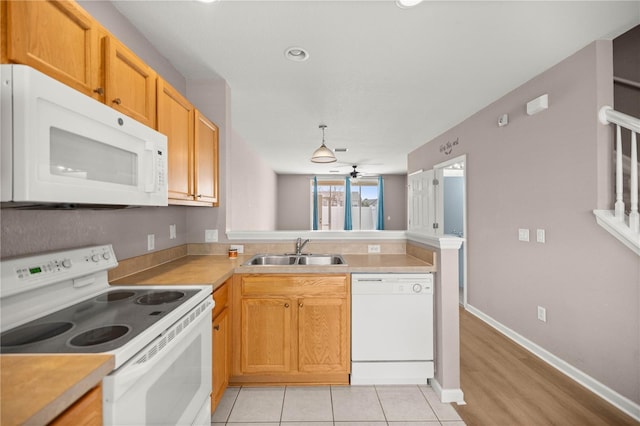 kitchen featuring light countertops, a sink, ceiling fan, white appliances, and a peninsula