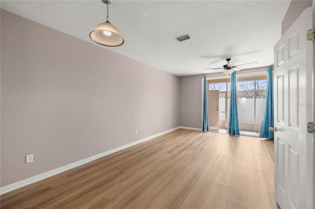 spare room with visible vents, a textured ceiling, light wood-style flooring, and baseboards