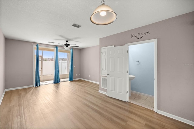 empty room featuring visible vents, ceiling fan, baseboards, and wood finished floors