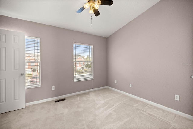 spare room featuring light carpet, ceiling fan, visible vents, and baseboards