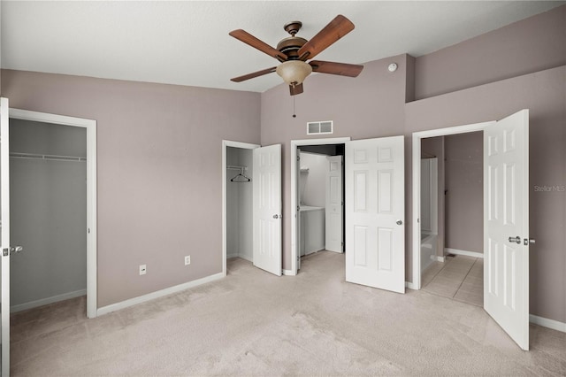 unfurnished bedroom with light colored carpet, visible vents, vaulted ceiling, and two closets