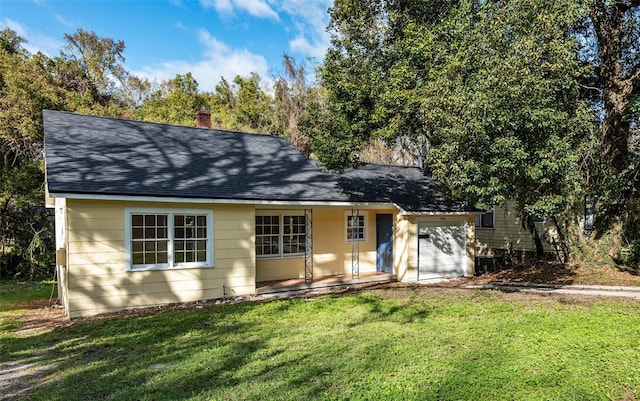 view of front of home with roof with shingles, a chimney, a garage, driveway, and a front lawn