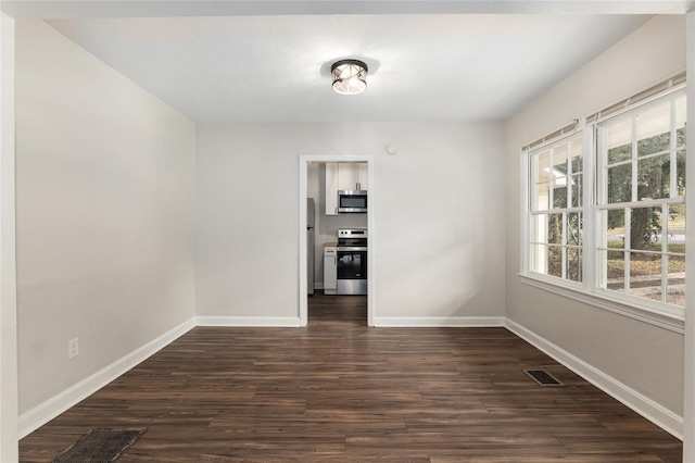 unfurnished dining area with dark wood-type flooring, visible vents, and baseboards