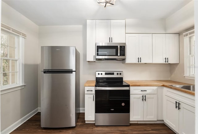 kitchen with plenty of natural light, butcher block countertops, appliances with stainless steel finishes, and white cabinets